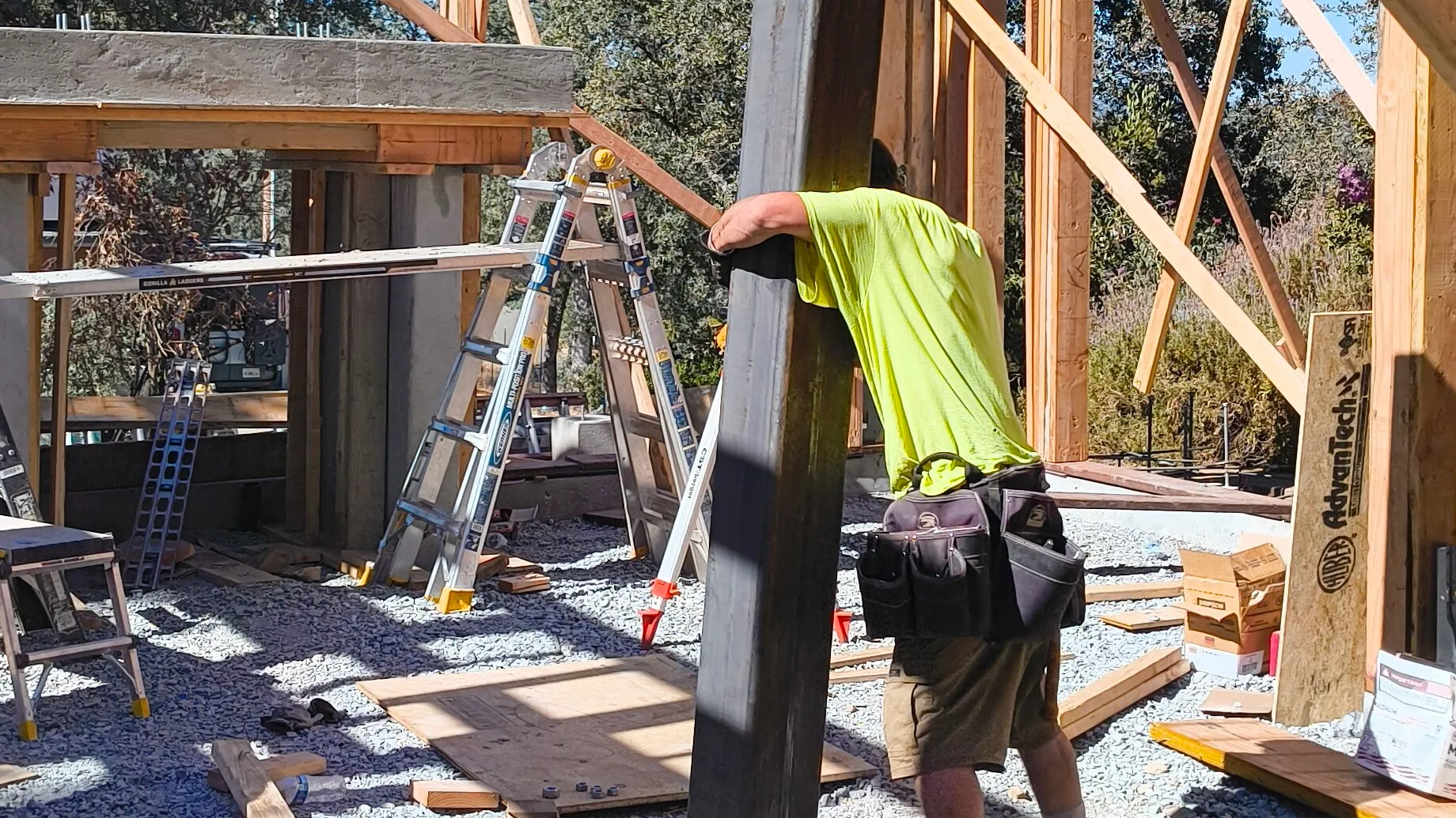 A CCI Builders carpenter carrying a steel post on a framing job